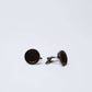 Round black cufflinks with textured center on plain white background