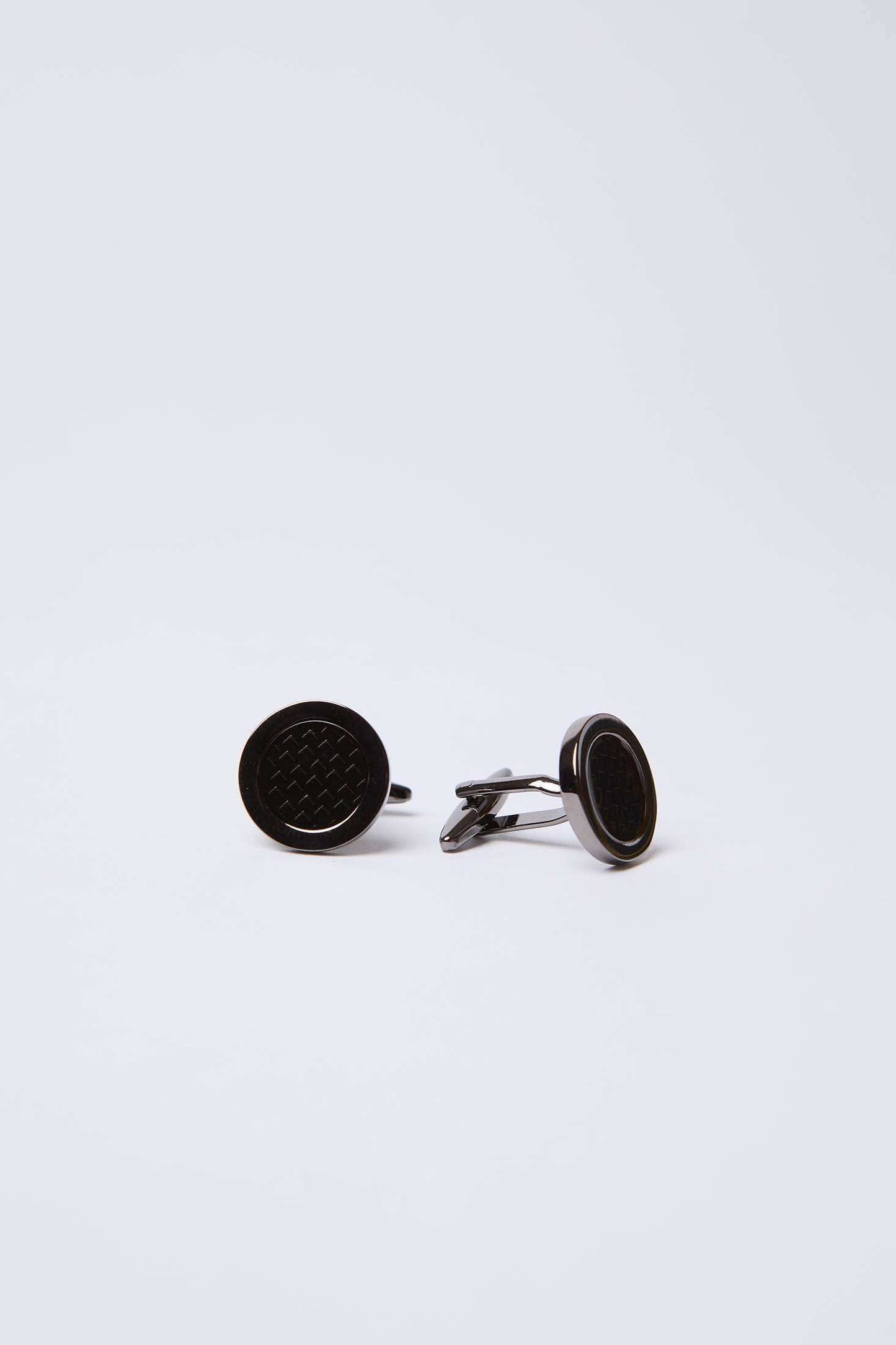 Round black cufflinks with textured center on plain white background