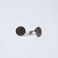 Round silver cufflinks with black engraved swirl pattern on a white background