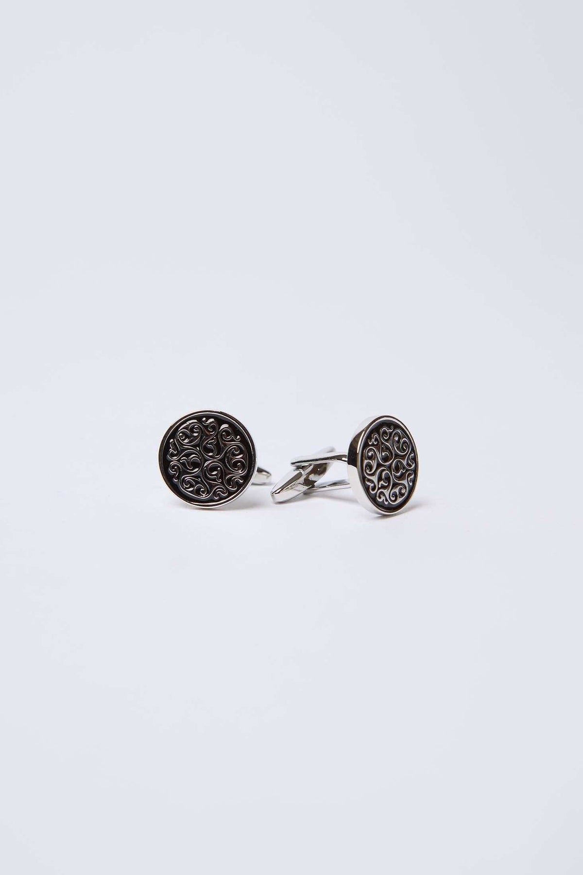 Round silver cufflinks with black engraved swirl pattern on a white background