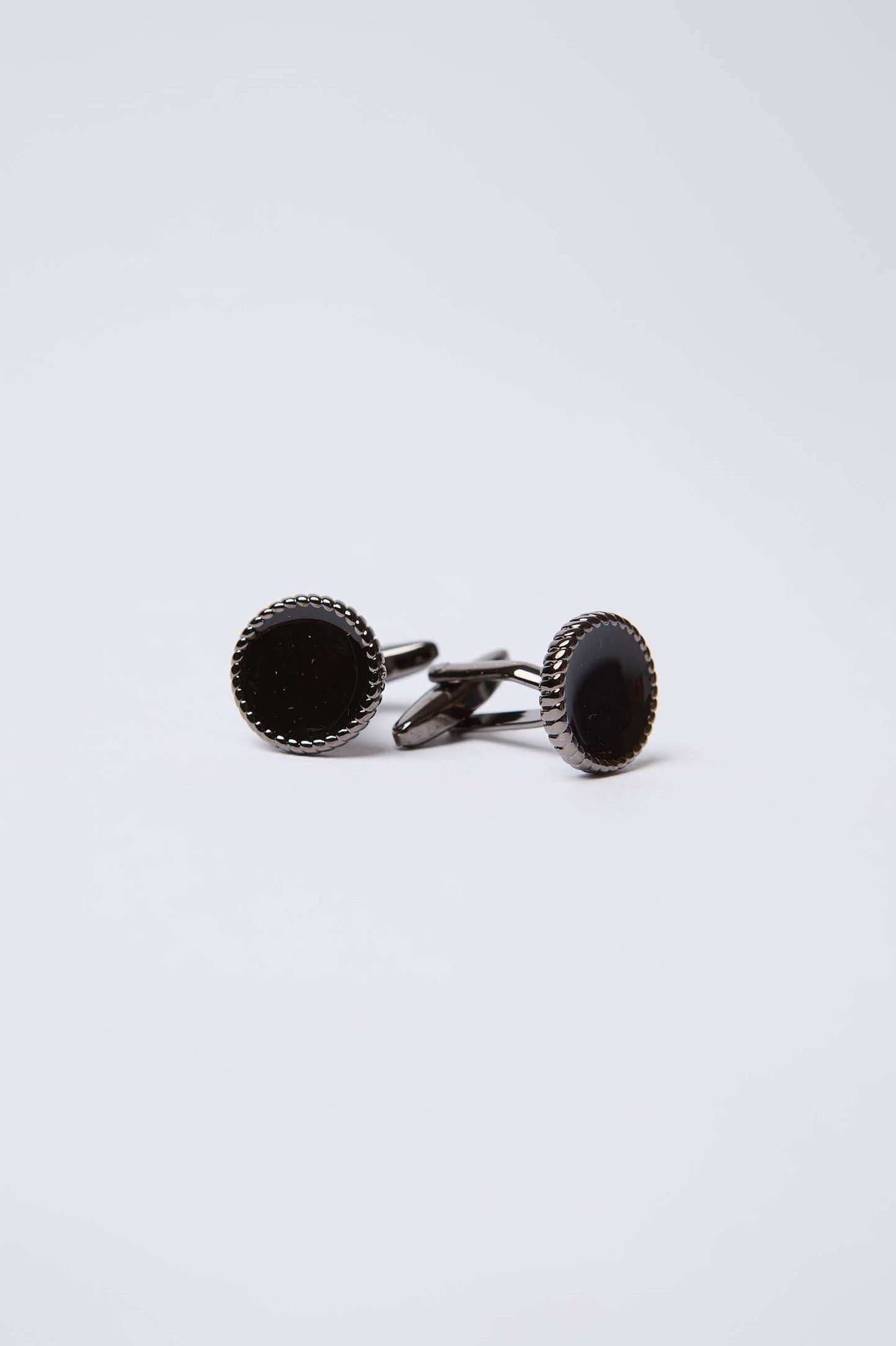 Elegant round black cufflinks with silver textured edge on a plain white background