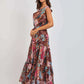 Woman wearing a sleeveless floral maxi dress with brown, pink, and blue tropical print