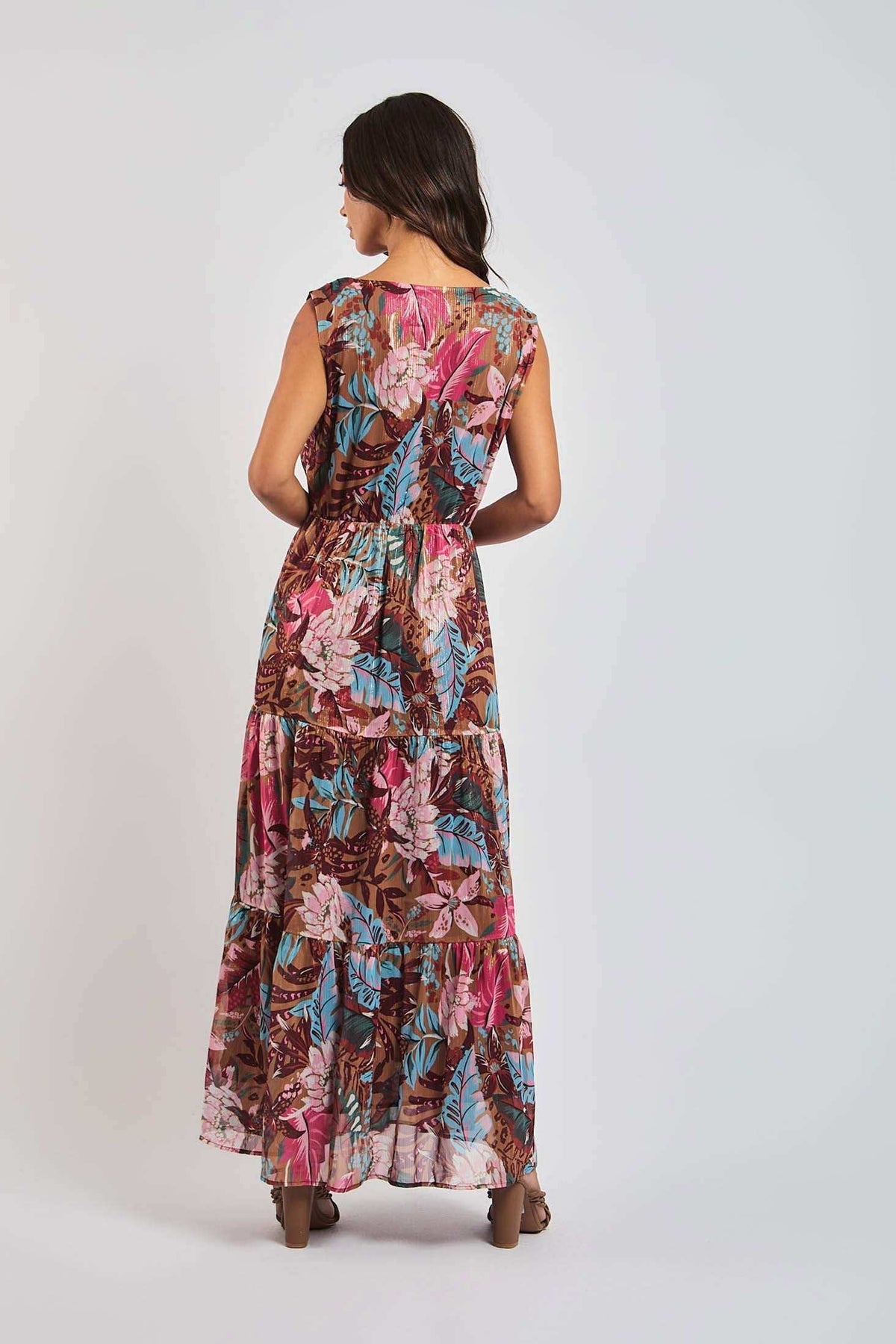 Woman in a sleeveless, floral print maxi dress with pink, blue, and brown tropical patterns