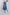 Woman wearing pleated denim midi skirt with frayed hem and casual sneakers on white background