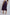 Woman wearing a high-waisted purple midi skirt with white sneakers, back view