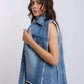 Woman wearing sleeveless frayed blue denim vest and purple pants on white background