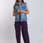 Woman wearing sleeveless denim vest and purple cargo pants with white sneakers