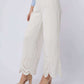 Woman wearing white wide-leg pants with lace hem, light blue blouse, and nude heels