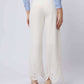 Woman wearing wide-leg white pants with eyelet lace hem and blue button-up shirt