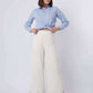 Woman wearing a light blue button-up shirt and white wide-leg pants with lace hem