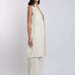 Woman wearing sleeveless cream long vest, matching wide-leg pants, and woven flats