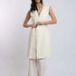 Woman wearing sleeveless beige long vest with matching wide-leg pants and woven slip-ons