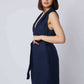 Woman wearing sleeveless navy blue belted vest with deep V-neck, posing sideways