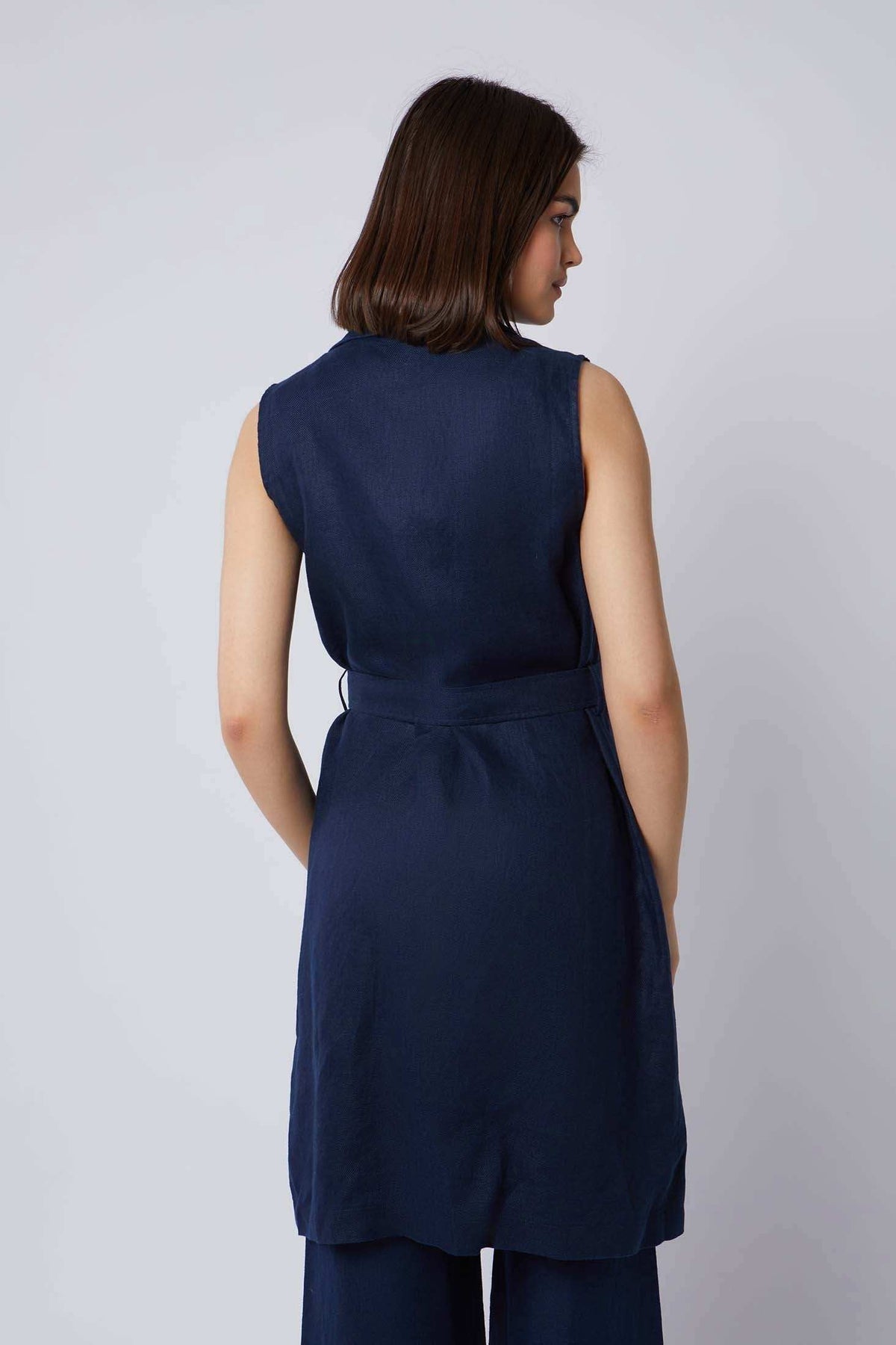 Woman wearing sleeveless navy tunic top with matching pants, back view, minimalist style