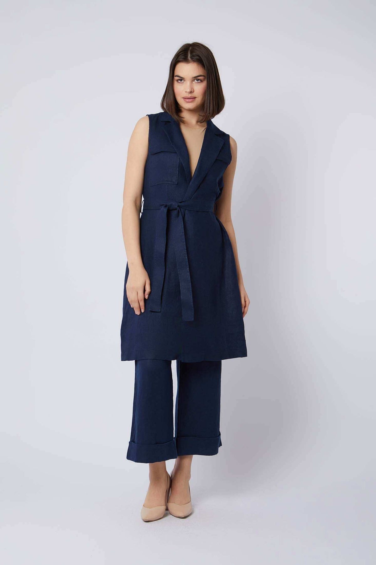 Woman wearing sleeveless navy belted tunic and wide-leg pants set, neutral heels