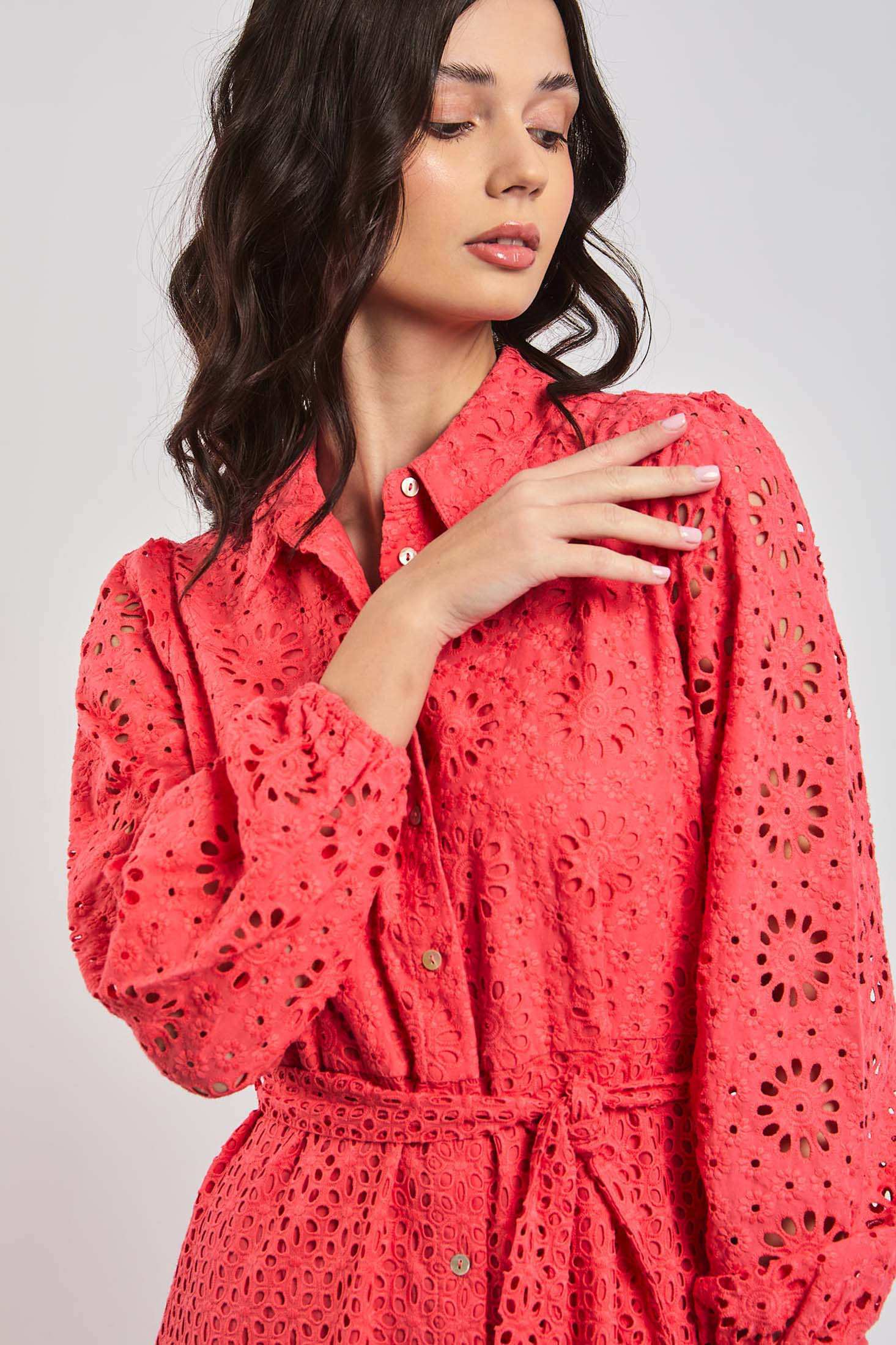 Woman wearing a Dalydress coral eyelet dress with floral cutout details and a waist tie.