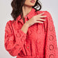 Woman wearing a Dalydress coral eyelet dress with floral cutout details and a waist tie.