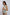Woman wearing sleeveless cream vest with blue floral embroidery and beige pants