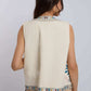 Woman wearing a sleeveless cream vest with colorful embroidered trim, viewed from the back