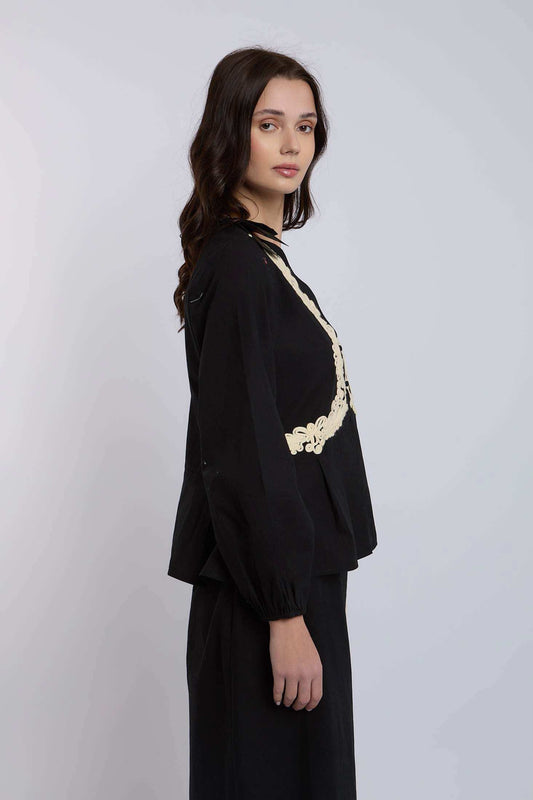 Woman wearing black long sleeve blouse with cream lace trim, side view