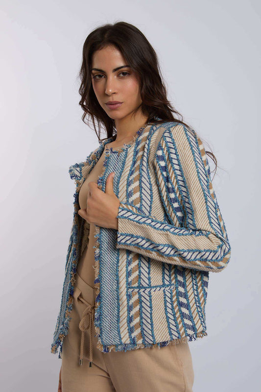 Woman wearing a beige and blue patterned woven jacket with frayed edges and neutral pants