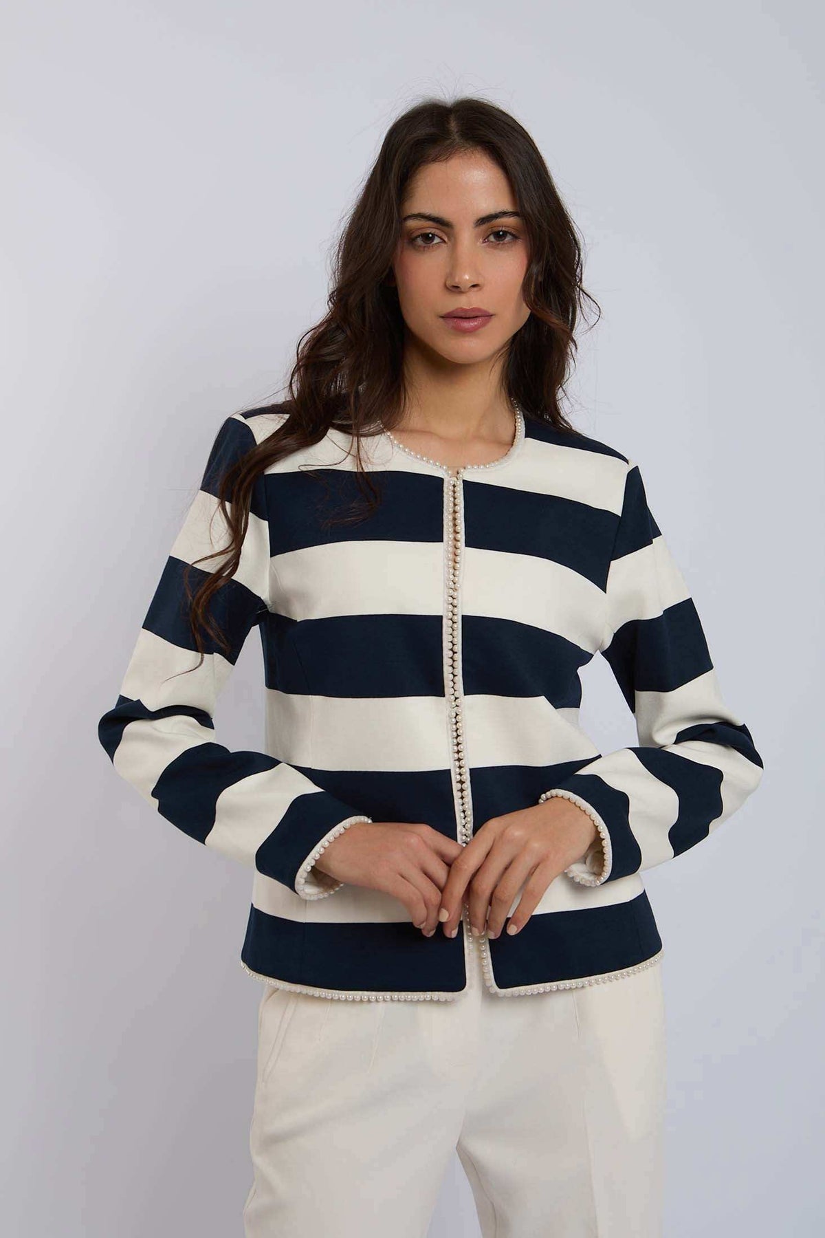 Dalydress women's striped navy and white blazer with pearl trim, white pants, studio background