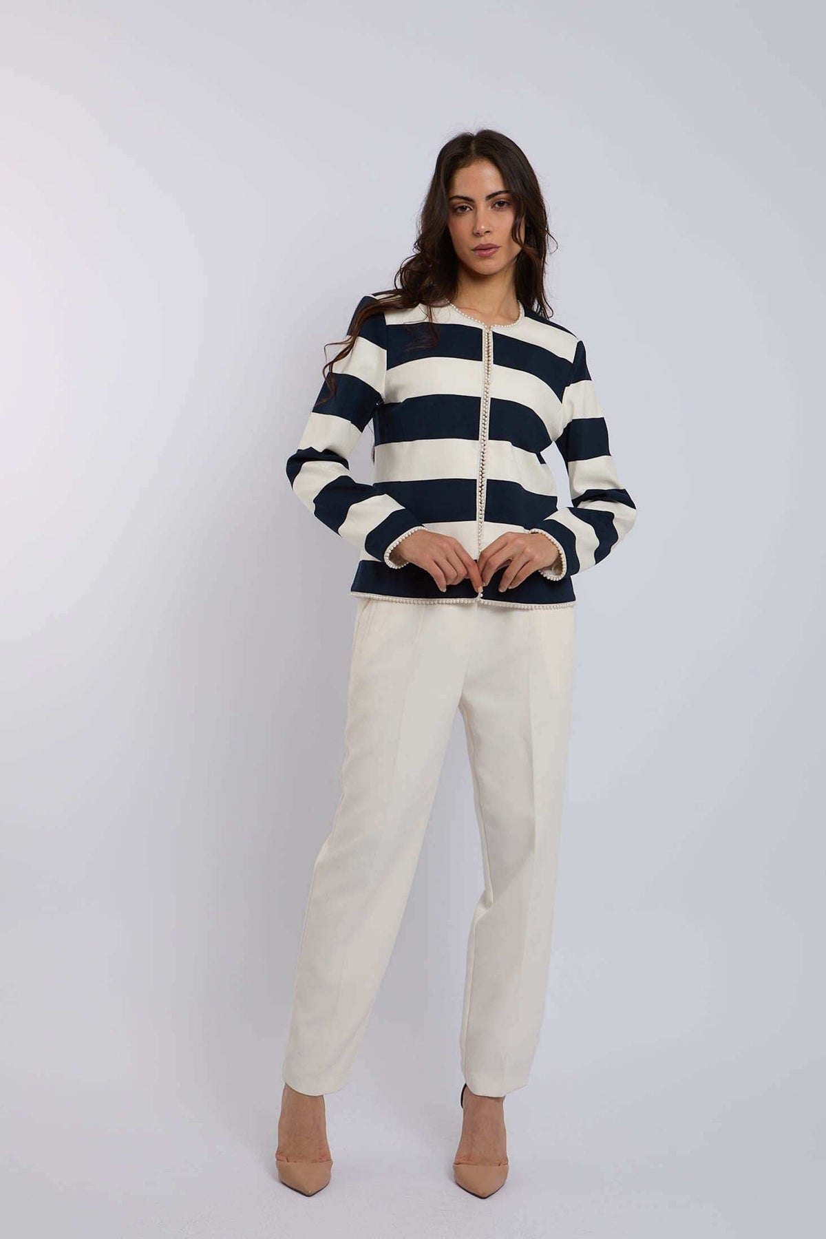 Woman modeling Dalydress navy and white striped jacket with cream trousers, studio background