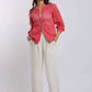 Woman wearing a pink eyelet bomber jacket with white wide-leg pants and white sneakers