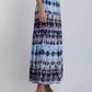 Woman wearing blue and black patterned maxi skirt with white sleeveless top and braided sandals