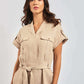 Woman wearing beige linen short-sleeve belted jumpsuit with front pockets