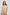 Woman wearing beige linen short-sleeve belted jumpsuit with front pockets