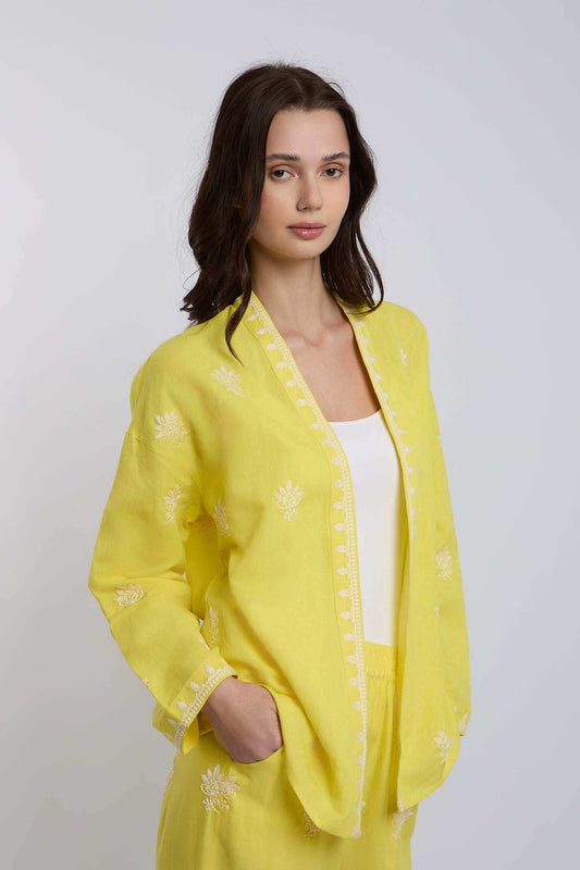 Woman wearing a yellow embroidered linen jacket and matching pants, casual outfit
