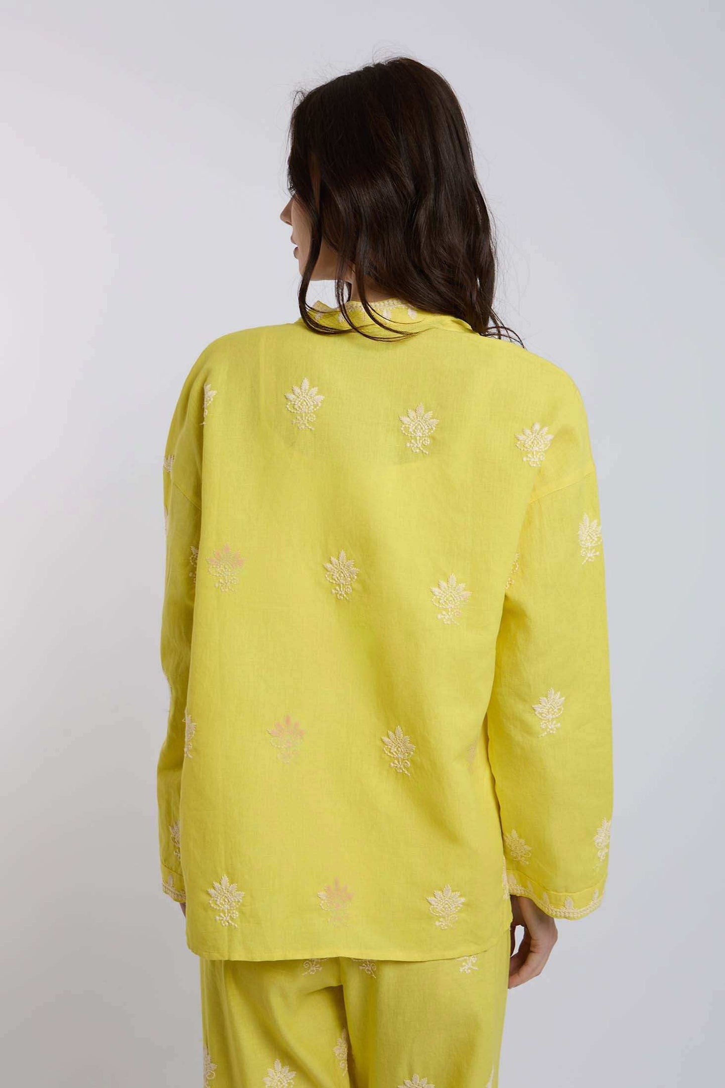 Woman wearing yellow embroidered long-sleeve shirt and matching pants, back view