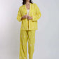 Woman wearing yellow embroidered pantsuit with white floral patterns, standing indoors