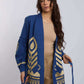 Woman wearing blue open-front jacket with gold geometric embroidery, beige shirt and pants
