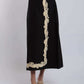 Black midi skirt with beige floral embroidery, styled with braided sandals