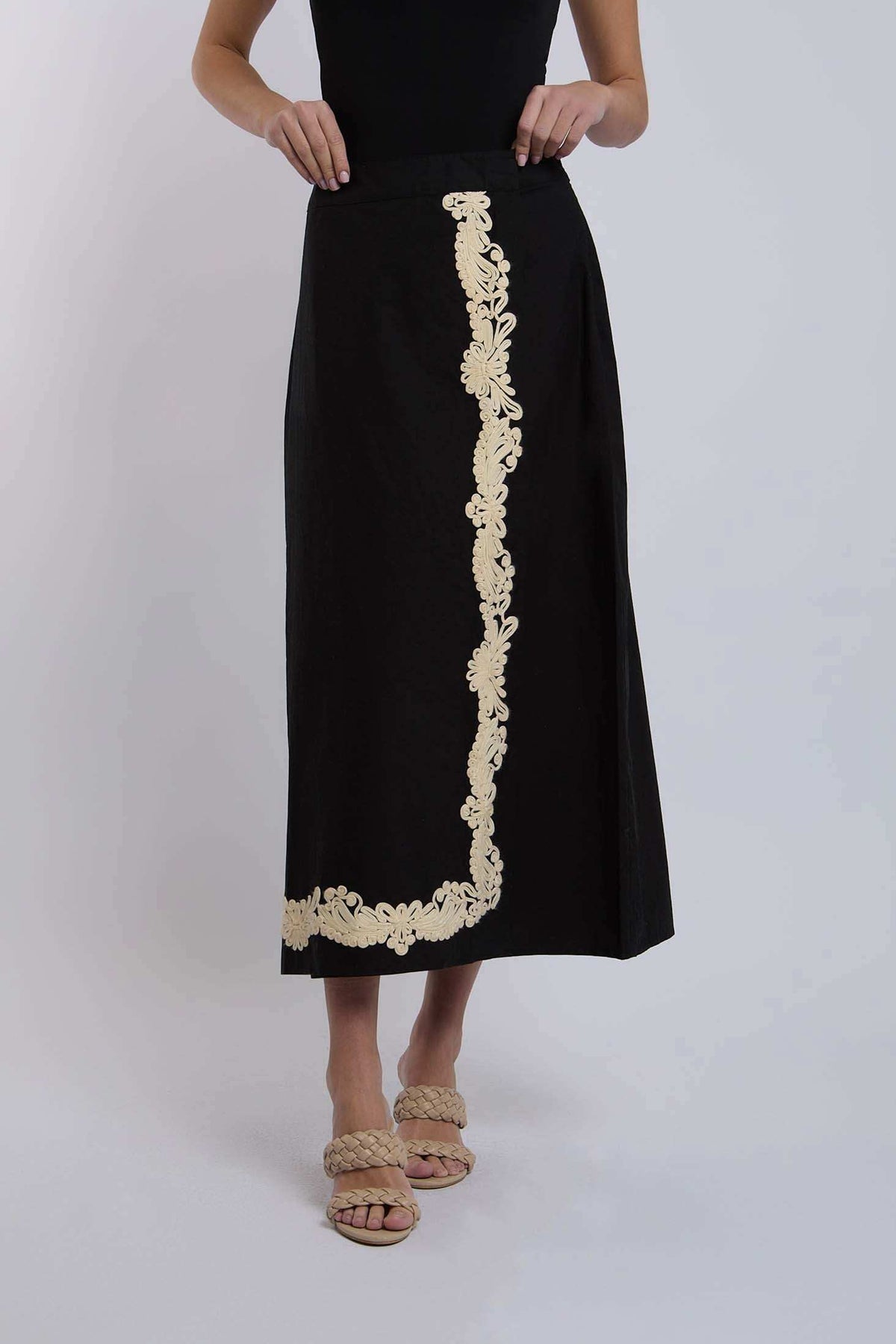 Black midi skirt with beige floral embroidery, styled with braided sandals