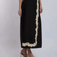Black midi skirt with beige floral embroidery, worn by woman in heeled sandals