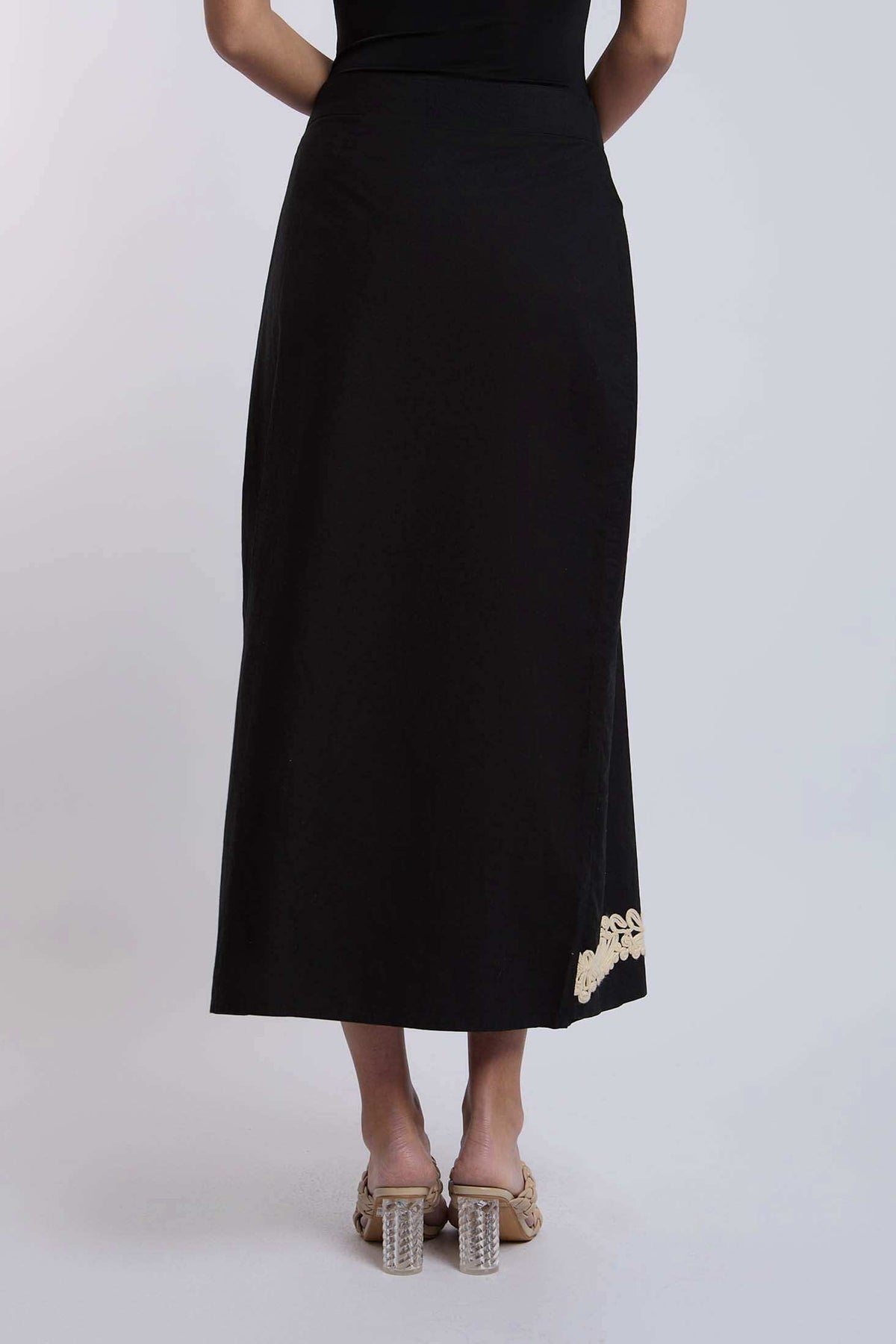 Black women's midi skirt with beige embroidery at hem, styled with nude heeled sandals