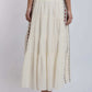Woman wearing a tiered cream maxi skirt with side embroidery, back view.