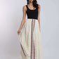 Woman wearing a sleeveless black top and long cream maxi skirt with red embroidered patterns