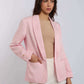 Woman wearing a light pink blazer, beige top, and white trousers in studio setting