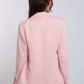 Woman wearing a light pink blazer and white pants, back view, casual fashion style