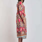 Woman wearing a long-sleeve, colorful paisley midi dress with floral patterns