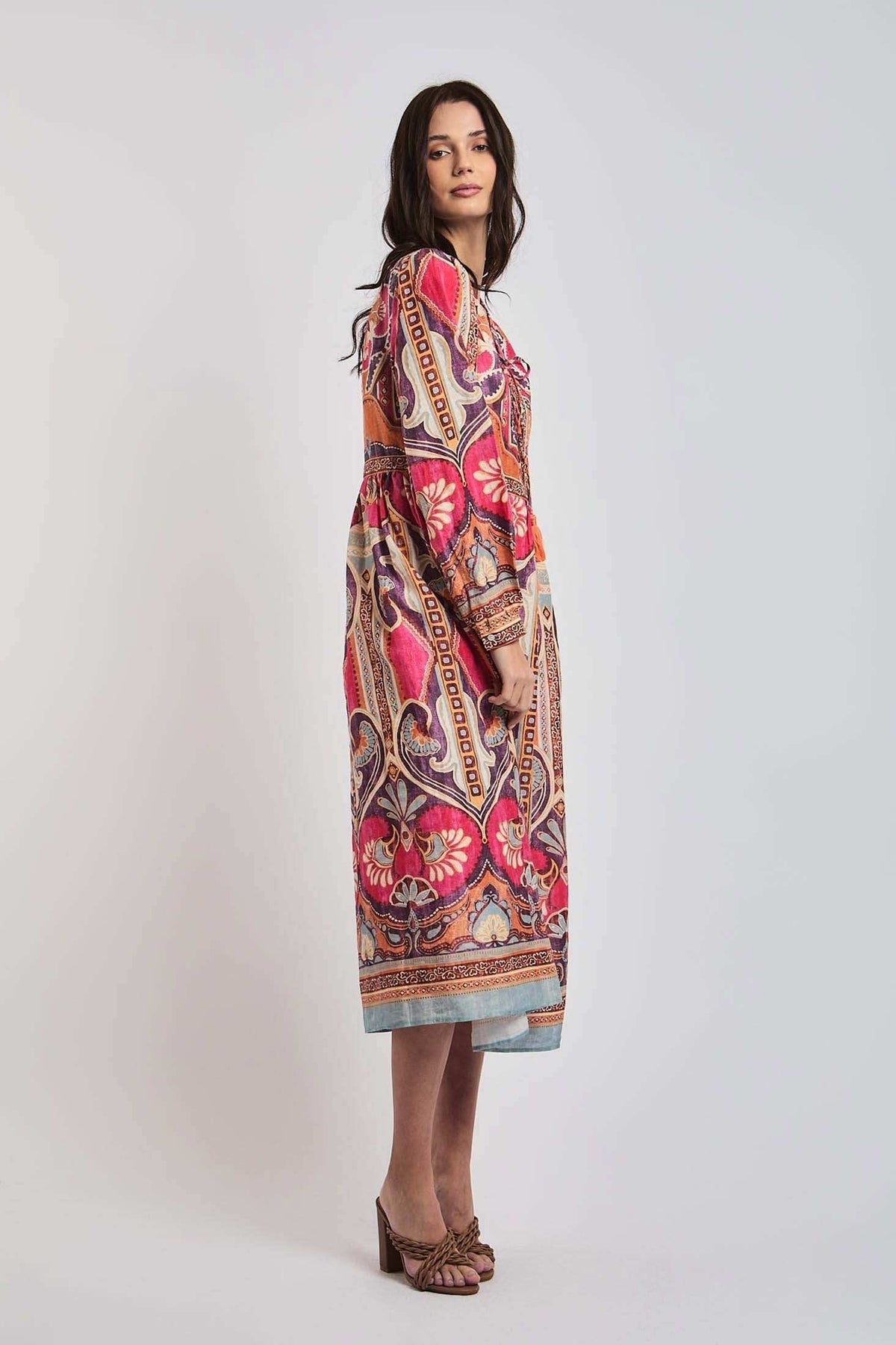 Woman wearing a long-sleeve, colorful paisley midi dress with floral patterns