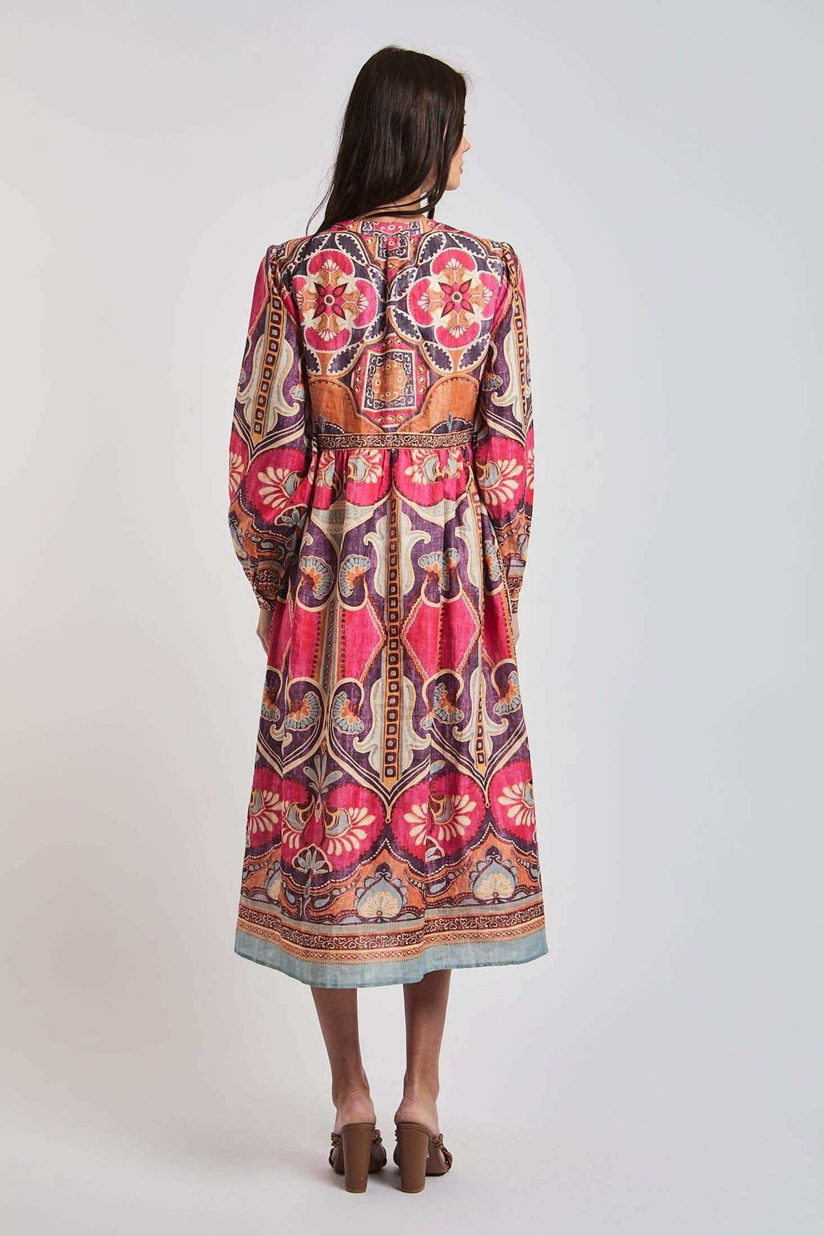 Woman wearing a long-sleeve, colorful floral boho midi dress, shown from the back