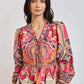 Woman wearing a colorful bohemian long-sleeve dress with vibrant geometric and floral patterns.