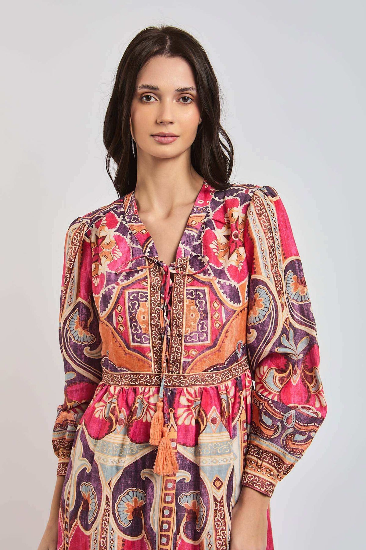 Woman wearing a colorful bohemian long-sleeve dress with vibrant geometric and floral patterns.