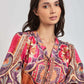 Woman wearing long sleeve blouse with vibrant geometric and floral patterns