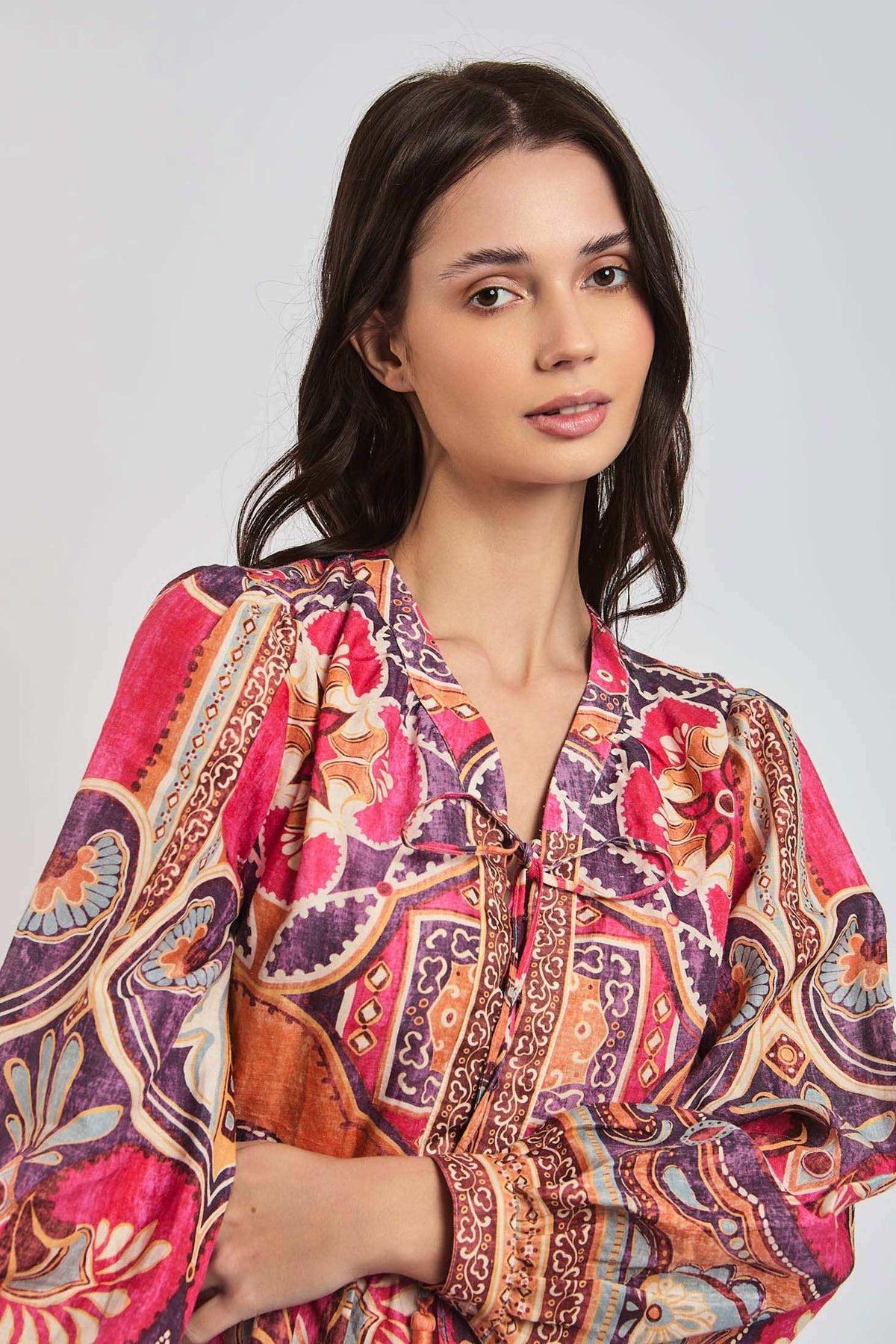 Woman wearing long sleeve blouse with vibrant geometric and floral patterns